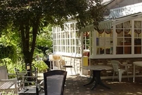 Shaded patio with tables and chairs beside the conservatory at Bridge House Care Centre